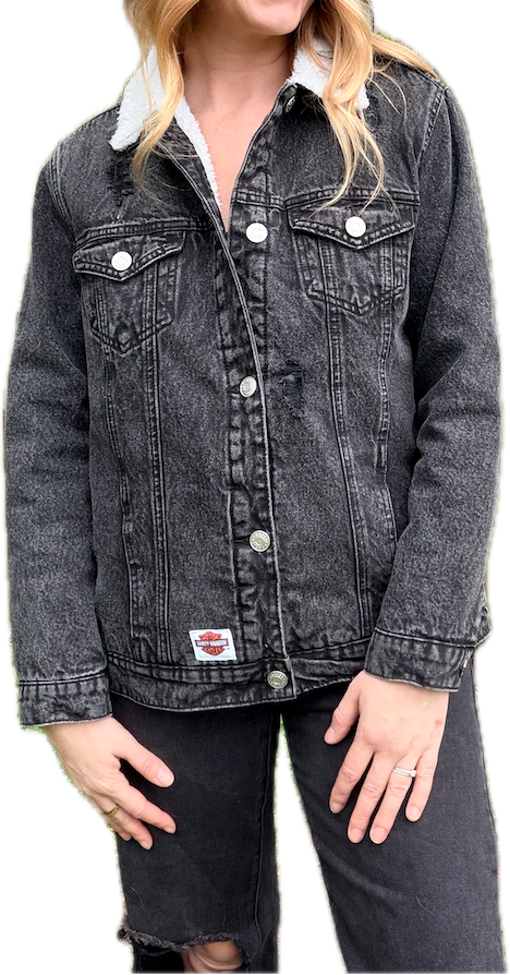 Woman wearing a black denim jacket with white buttons on a white background