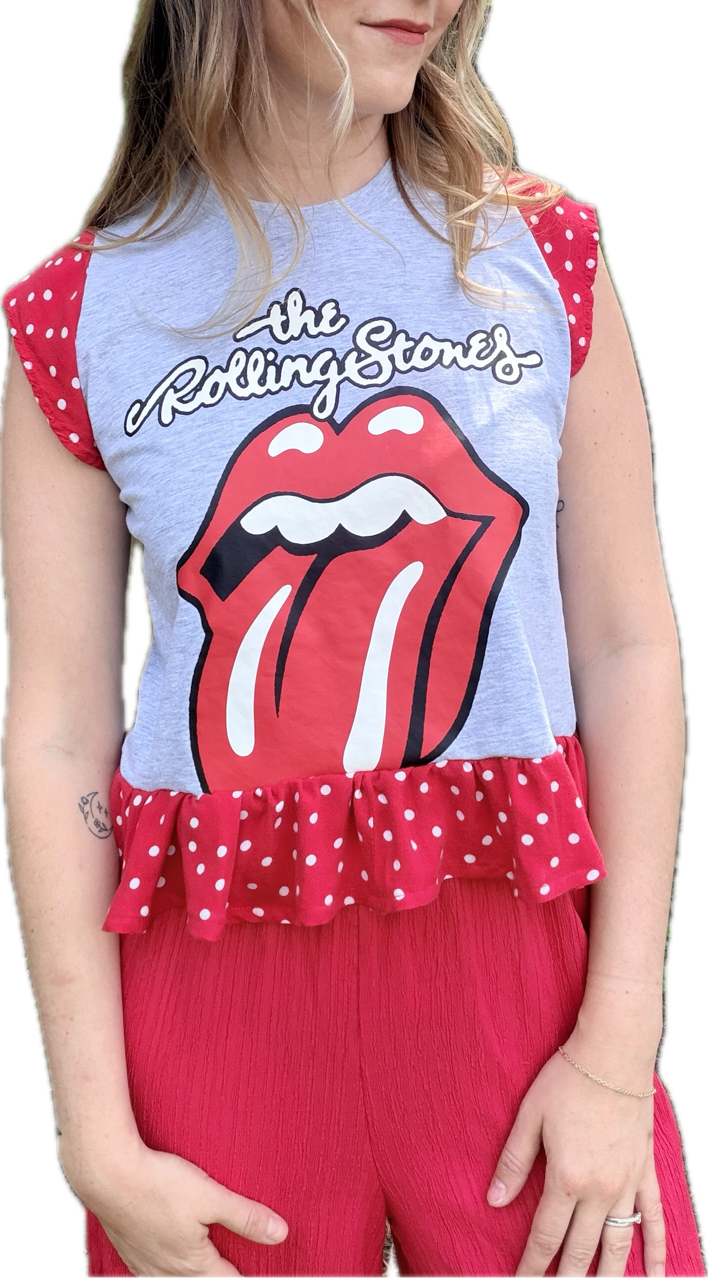 Woman wearing a sleeveless top with Rolling Stones logo and red pants on a white background